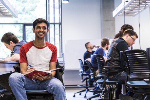 Student seated in a classroom with book in lap