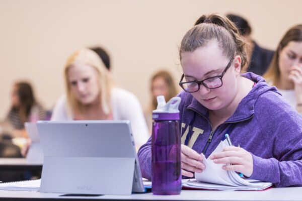 Student sitting in class looking through binder