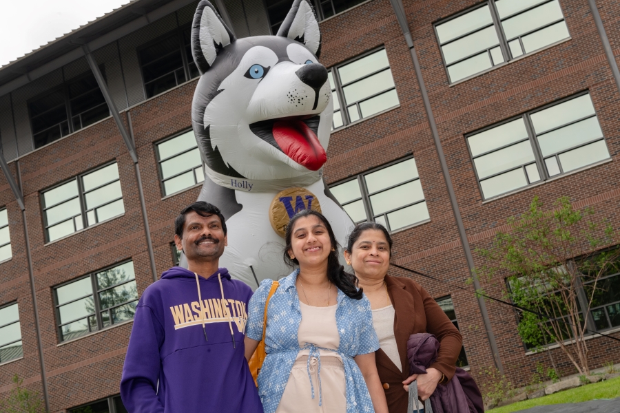 Student family posing in front of inflatable husky