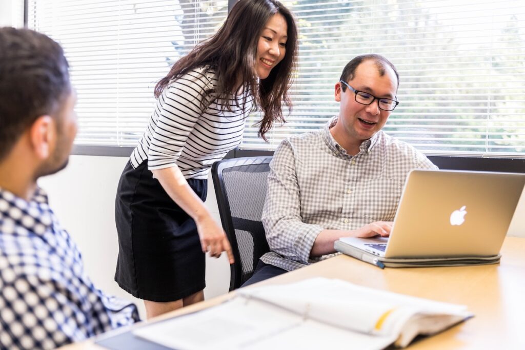 A person standing next to a person looking at a computer.