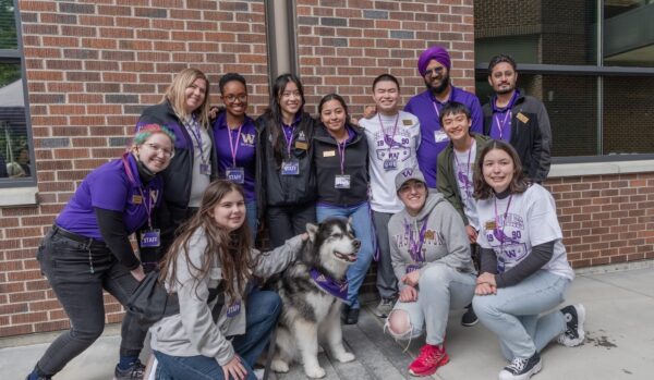Students posed around husky dog.