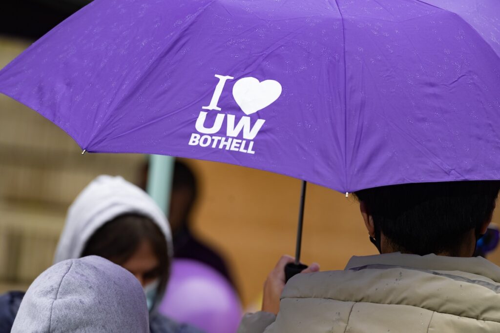 People gathered under a purple UW Bothell umbrella.