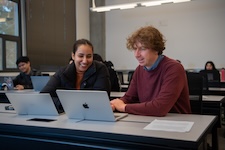 Two people collaborating at a table with laptops