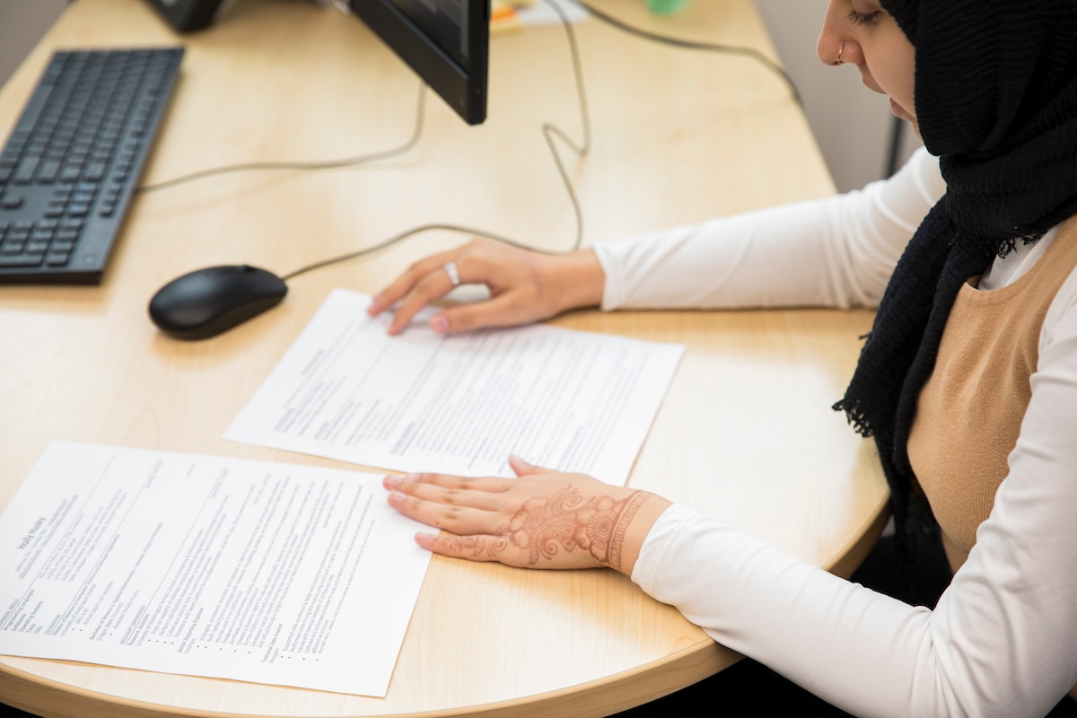 Student reviewing a document at a desk with a computer.
