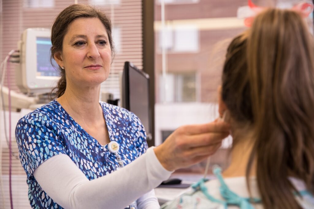 Person in scrubs examining a patient in a clinical setting.