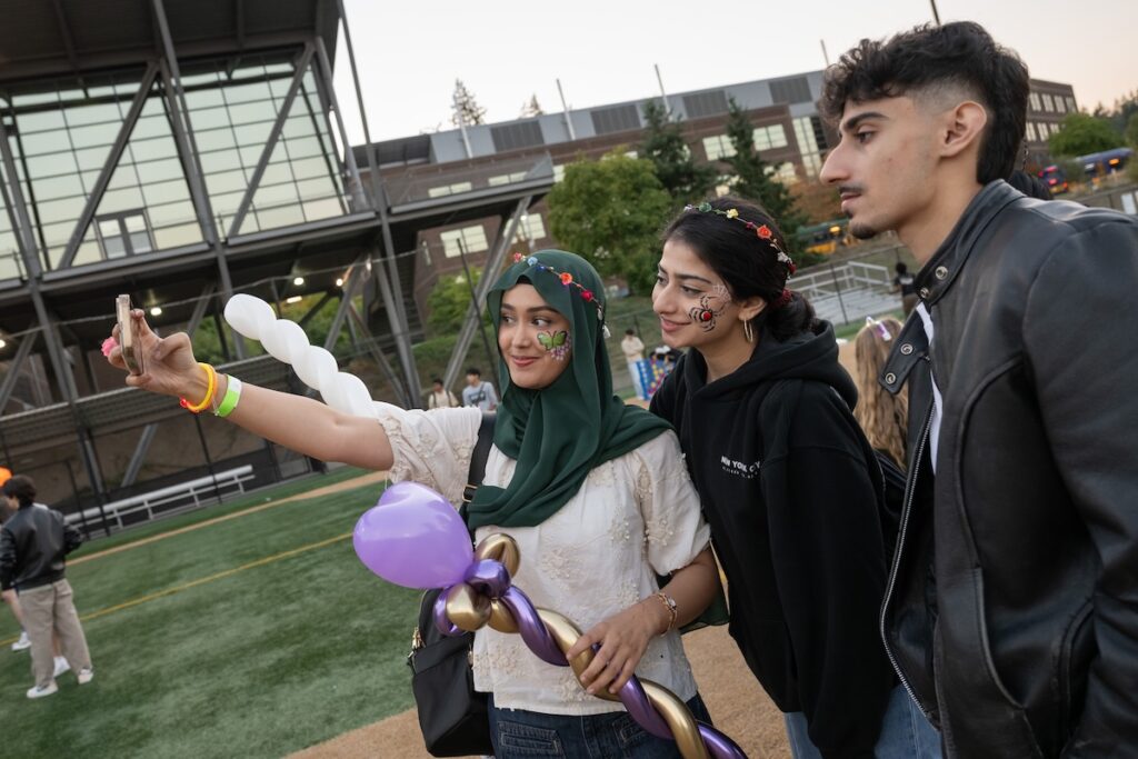 Three students taking a selfie at an outdoor campus event.