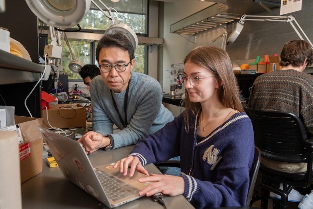 Two people collaborate on a laptop in a laboratory.