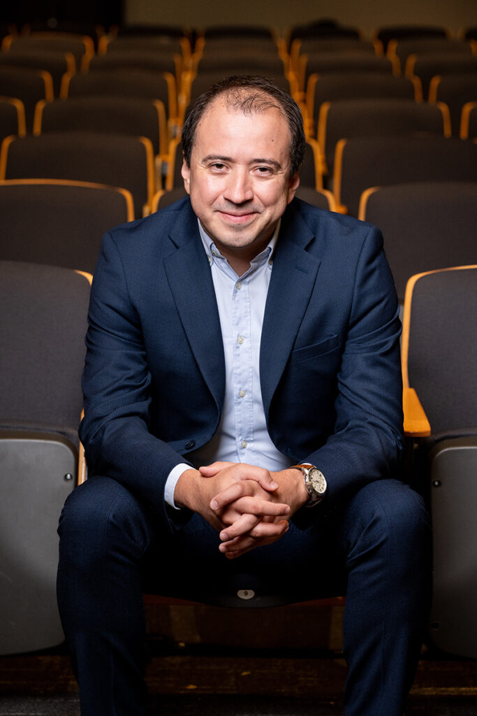 Alan Gonzalez sits with hands folded in a lecture hall at UW Bothell.