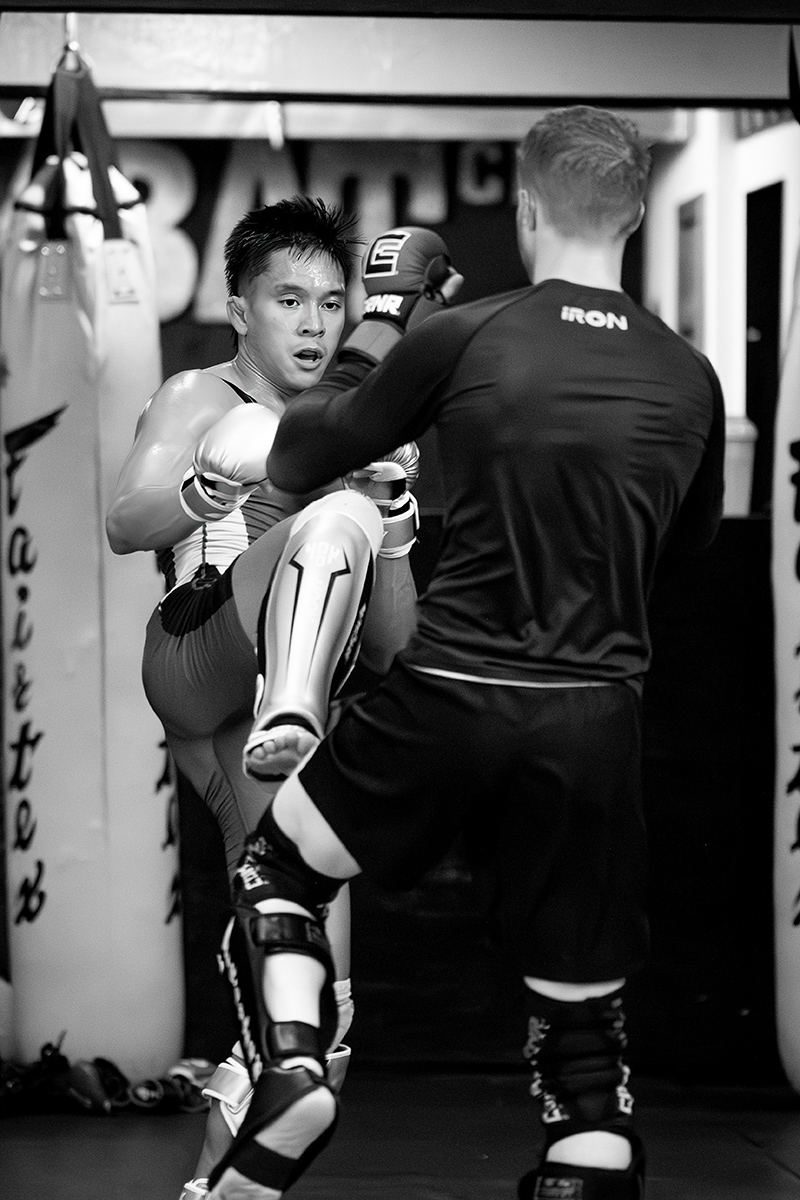 Bilal Hasan and a sparring partner are sparring at Charlie's Combat Club in Everett, Washington. Bilal, facing the camera, is in the process of kicking his opponent.