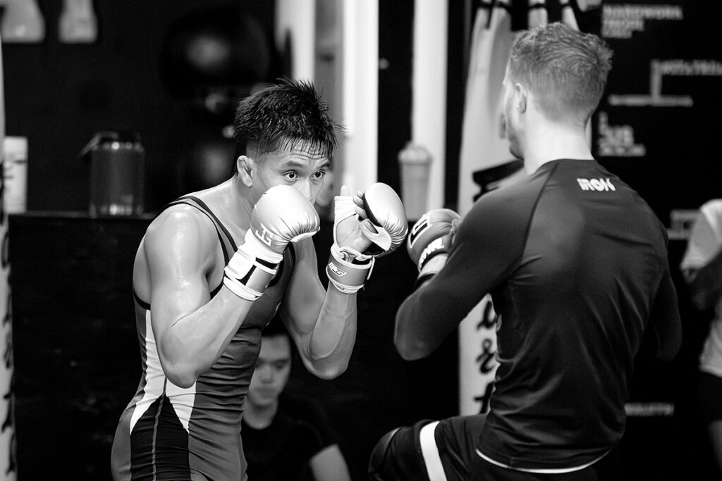 Bilal Hasan is sparring with a partner at Charlie's Combat Club in Everett, Washington. Bilal and his sparring partner are wearing exercise gear and mixed martial arts gloves. 