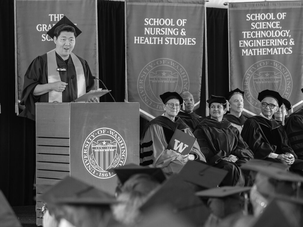 Jason Moon speaking from a podium during UW Bothell's graduate hooding ceremony.