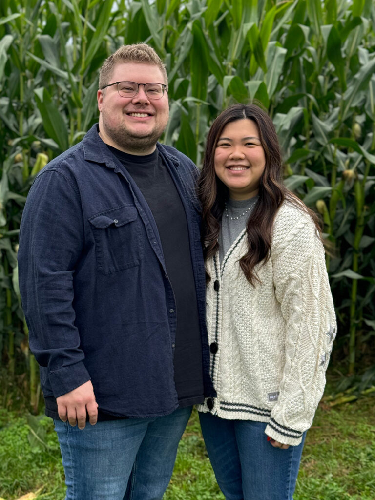 Taylor and Samantha Simms pose in front of corn stalks.