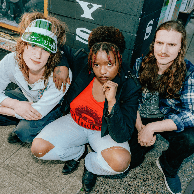 musical group The Maya Experience featuring 3 individuals crouched, looking up at the camera