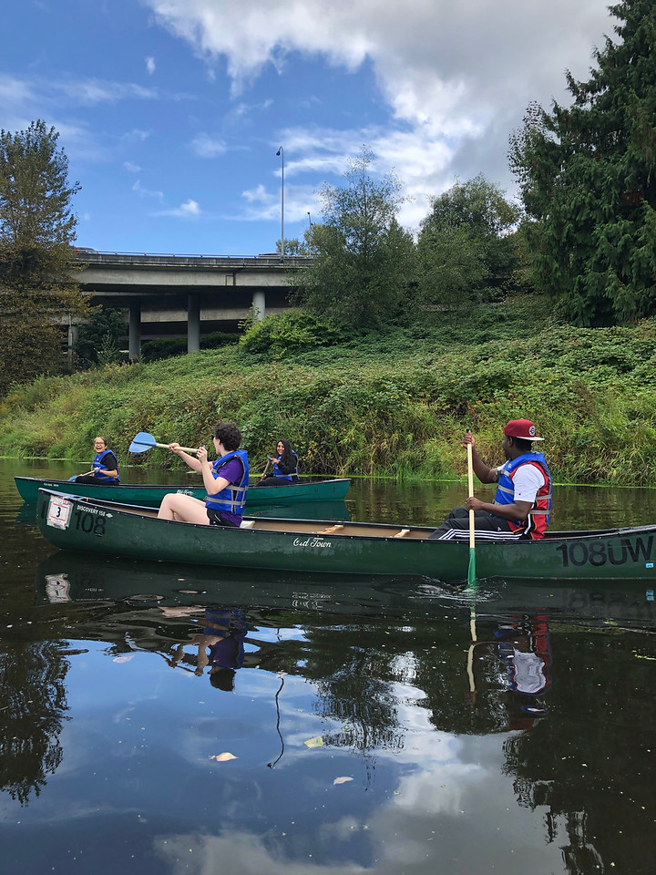Four students canoe on the river