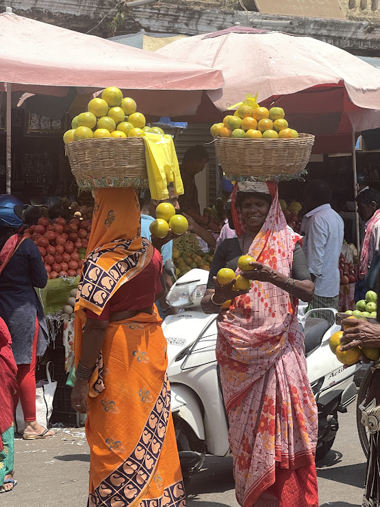 Fruit vendors with baskets on their heads selling their goods at a street market