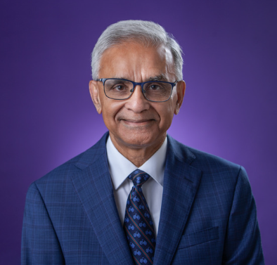 Dean Rajib Sanyal wearing a suit and smiling