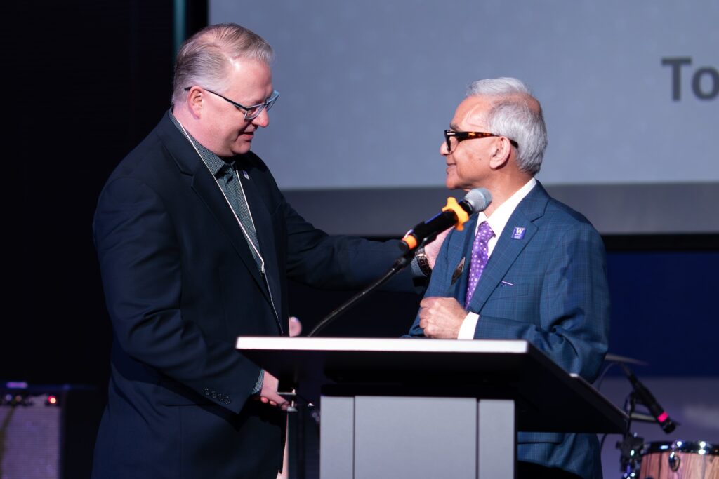 Tony Gepner and Dean Rajib Sanyal shaking hands at the podium