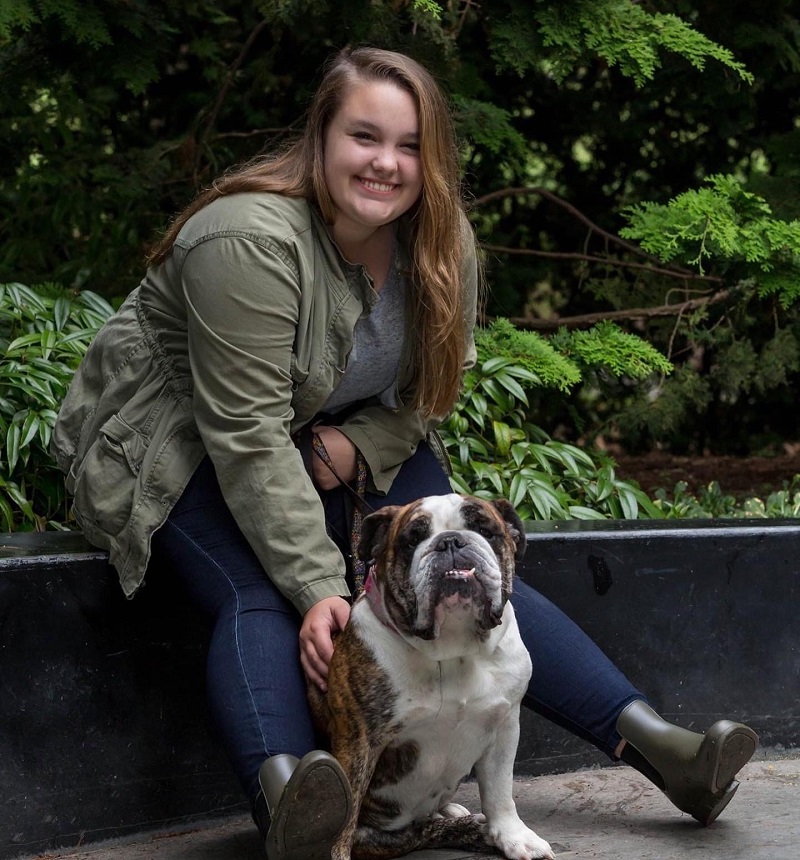 Ashley sits on bench and poses with her dog