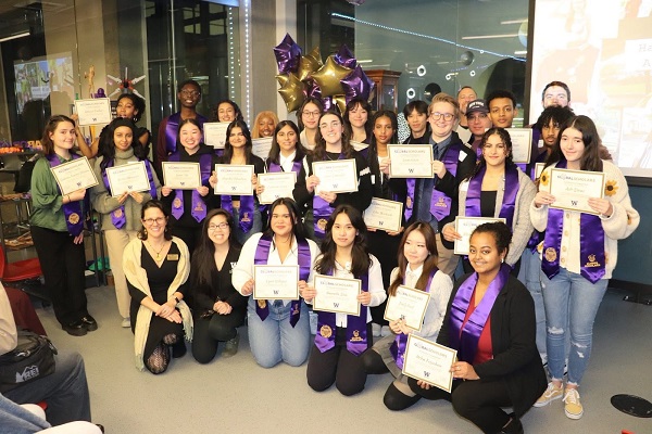 Student group holds certificates and wears their graduation stoles