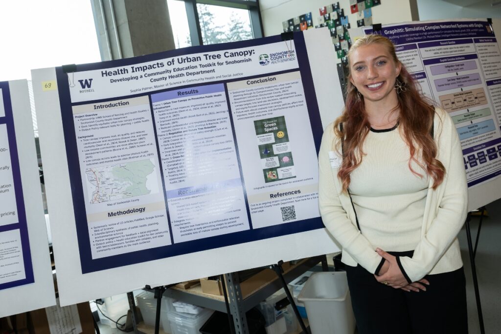 student smiles next to her poster