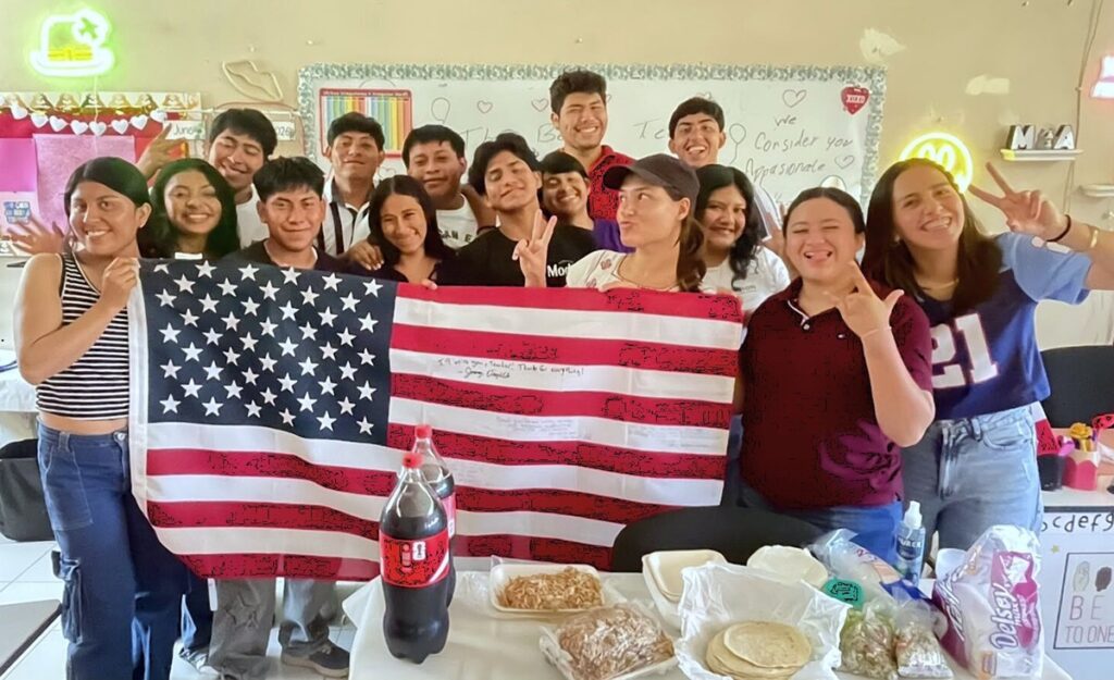 Sabrina and class or staff pose with US flag during celebration in classroom.