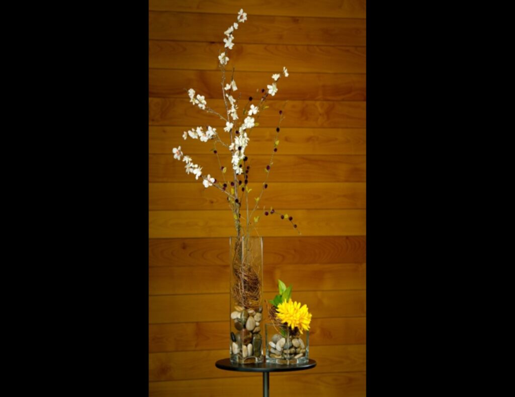 Tall flower vase with white flowers and short flower vase with yellow flowers.