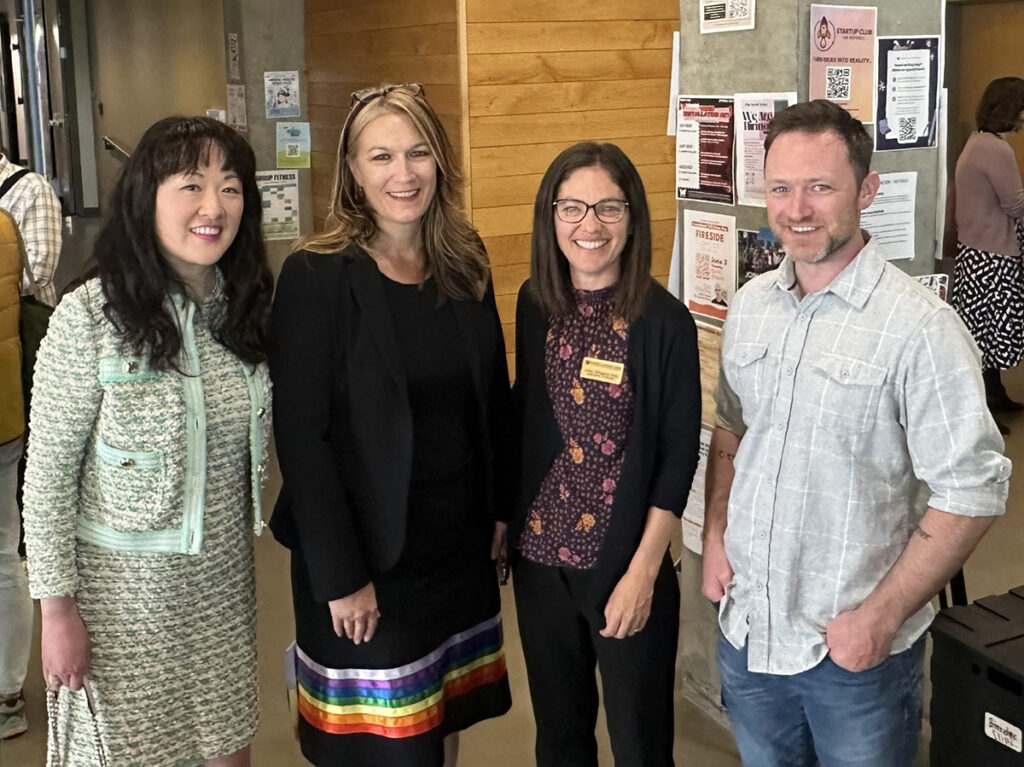Carol Miu, Dr. Jennifer McLoud-Mann, Dr. Joey Key and Jack Bayley pose in the hallway of a UW Bothell building.