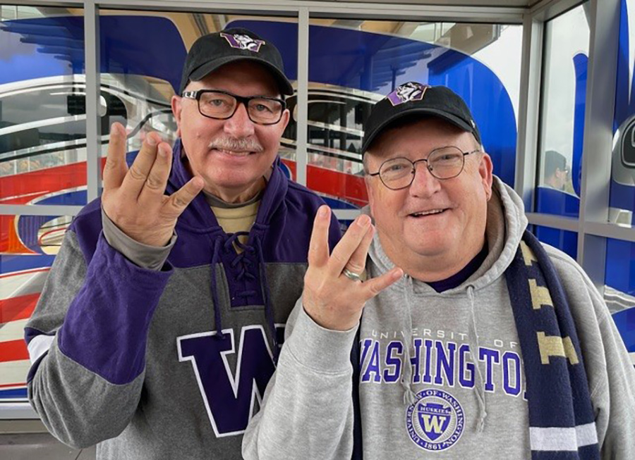 Portrait of Wicks and Portin in Washington gear, showing the "dubs" sign with their hands.