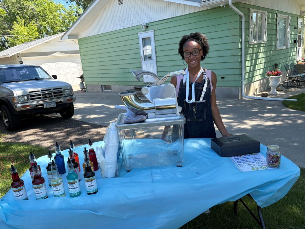 Hicks standing behind a table with snow cone equipment