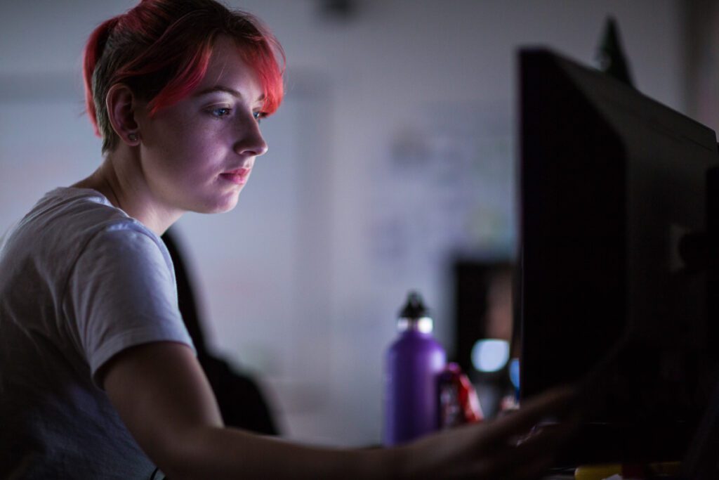 Student in a dark room looking at a computer screen