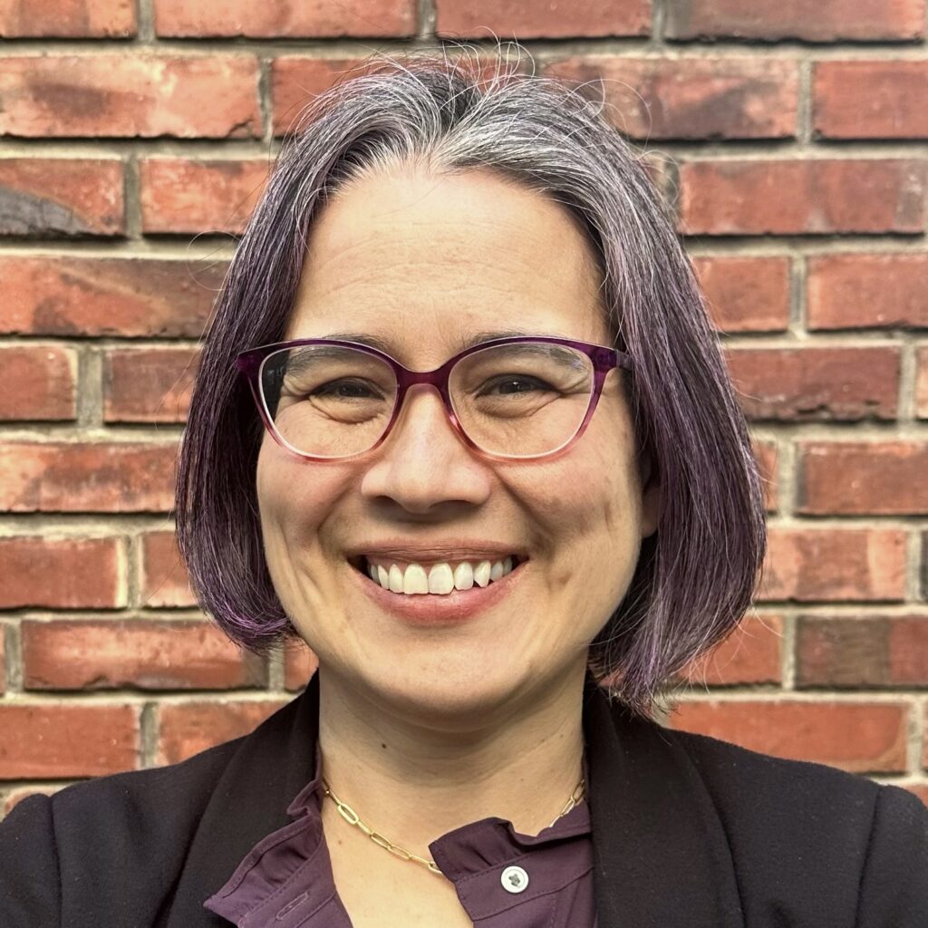 Woman smiling in front of brick wall