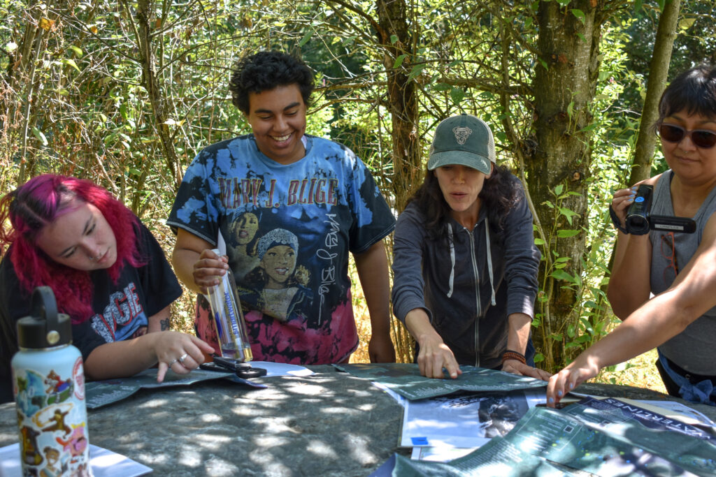 Four people gather around a boulder looking at a map.