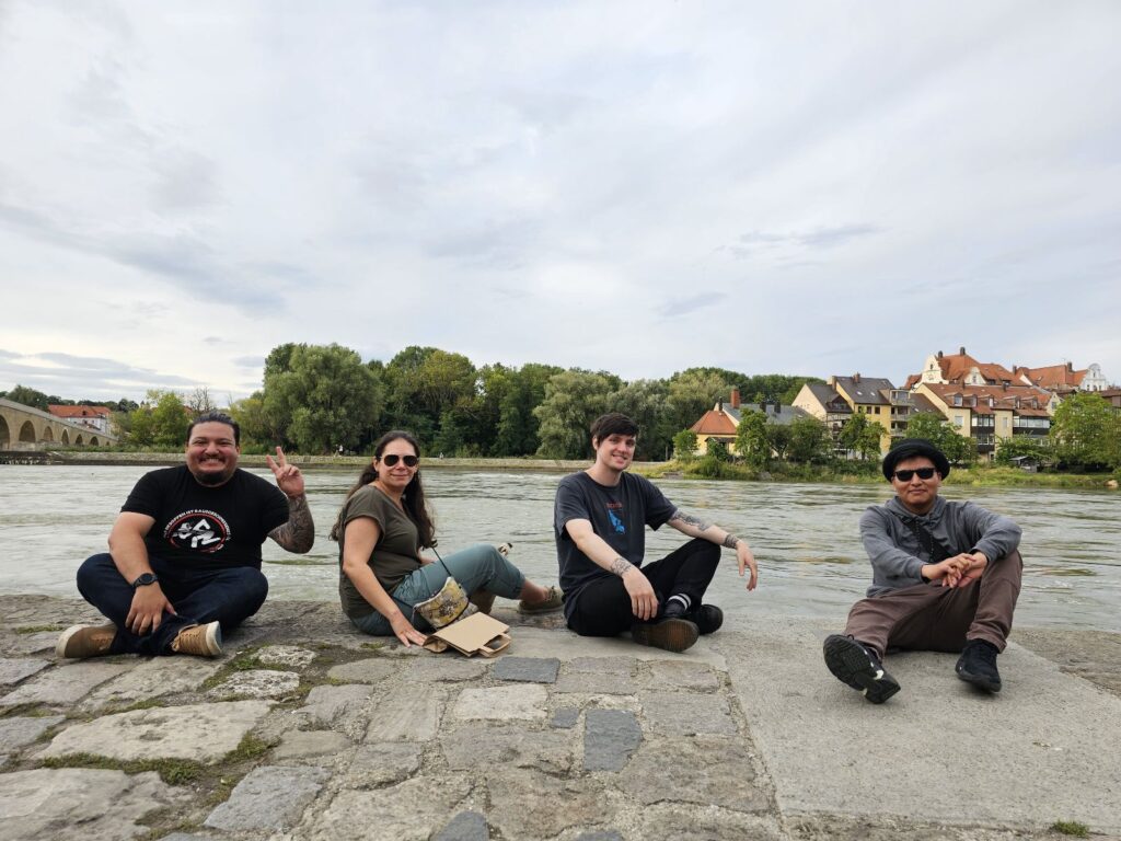 Four people sitting next to an urban waterway.