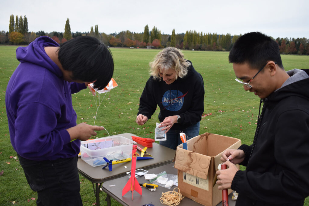 Three people at a table with model rocket supplies.