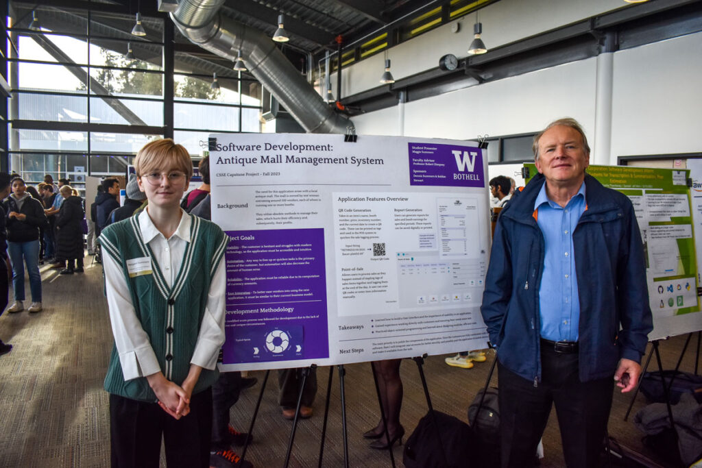 Two people standing next to a poster.