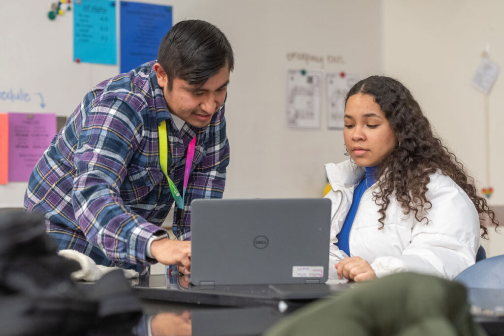 Two people look at a computer.