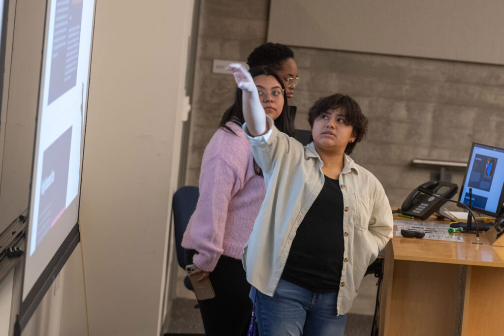 A person pointing to a projector screen.