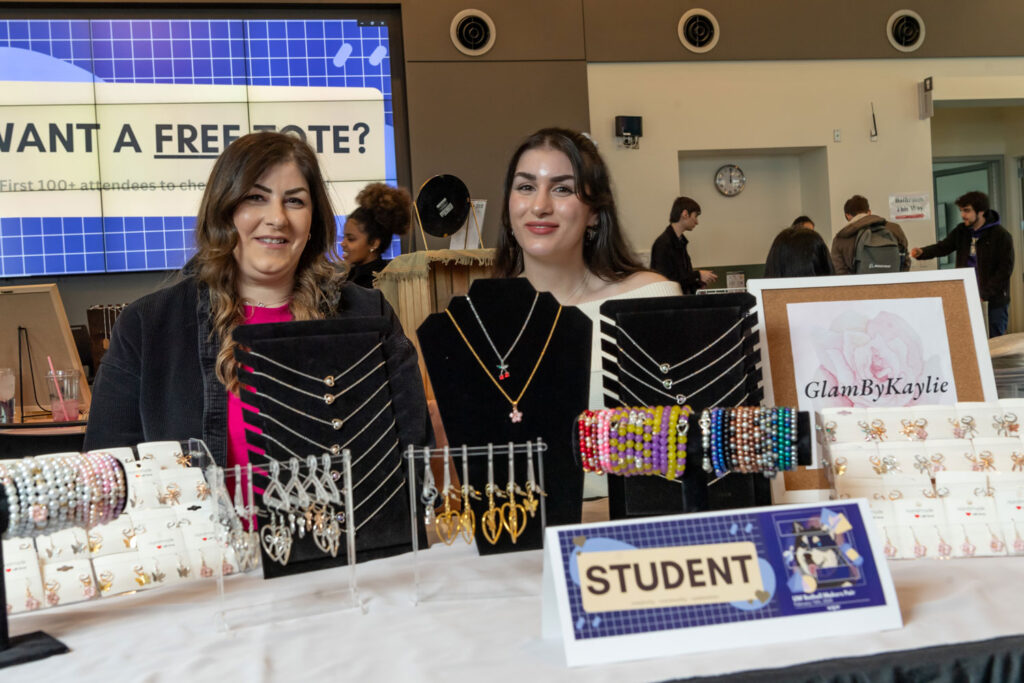 Two people behind a jewelry display.