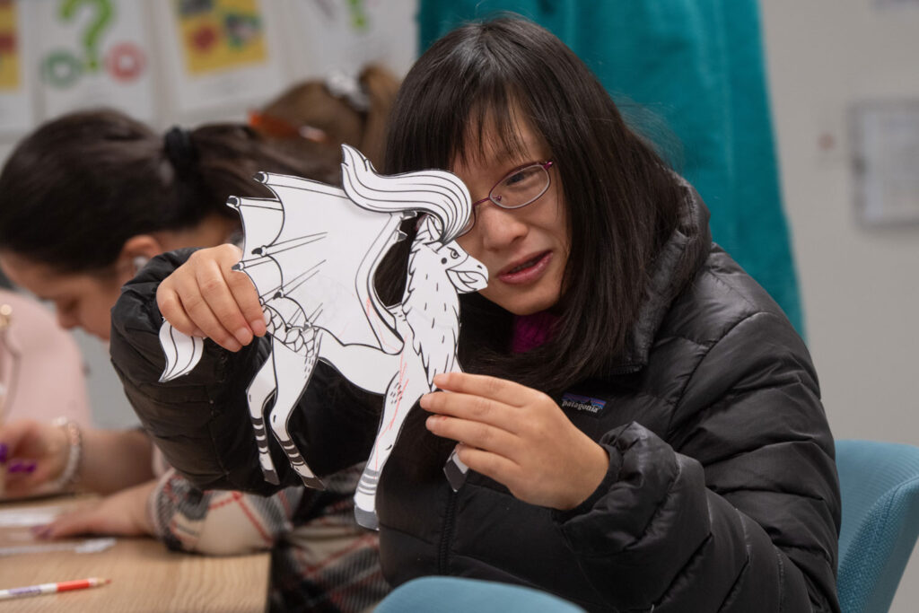A person holds up a piece of art with a mythical creature on it.
