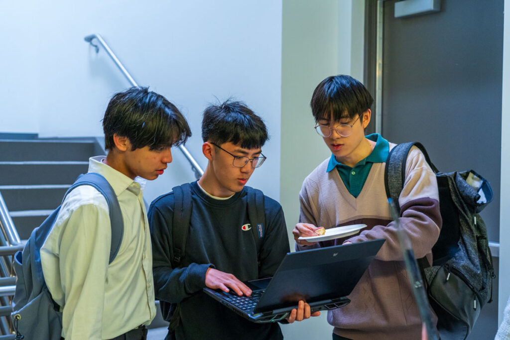 A group of people look at a computer.