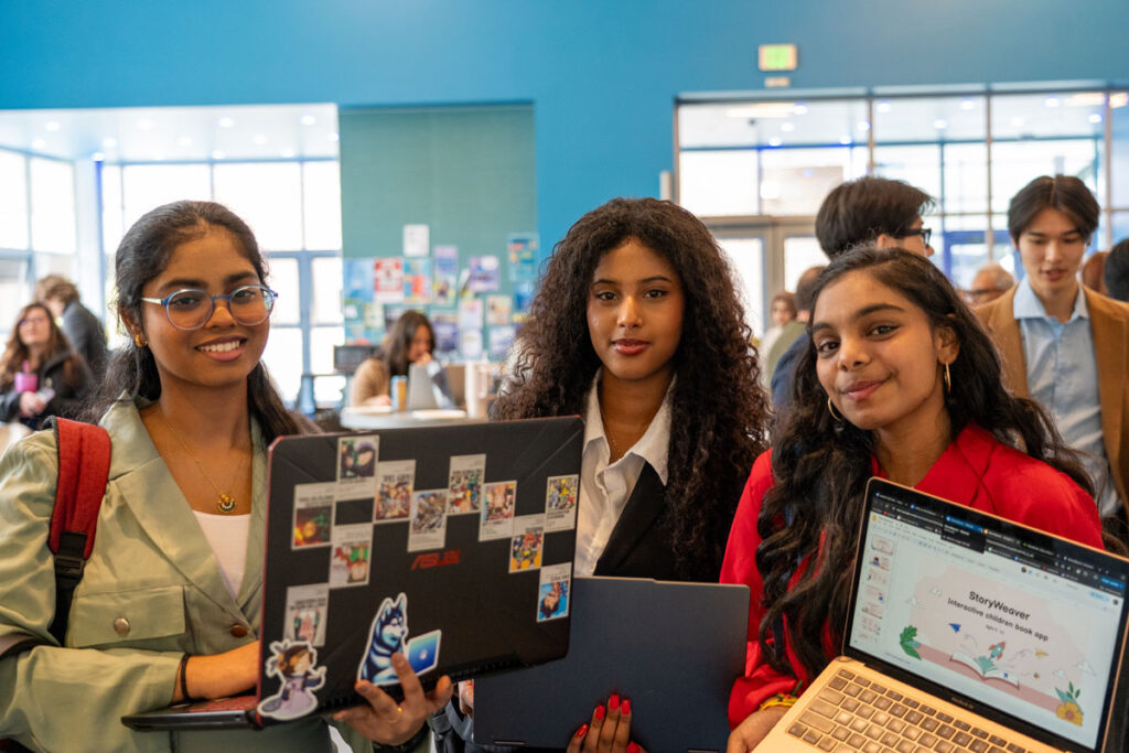 Three people holding computers.