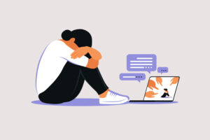 A graphic of a person holding their knees next to a computer with several alerts popping up.