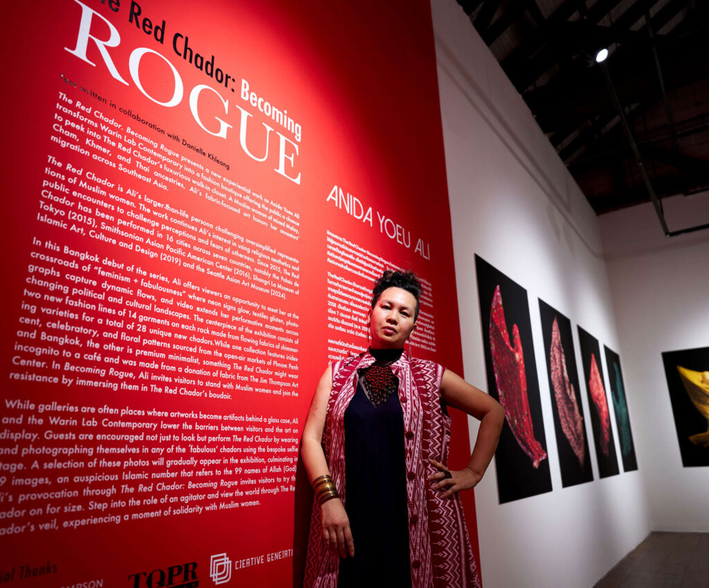 A person posing for a photo with an art exhibit.