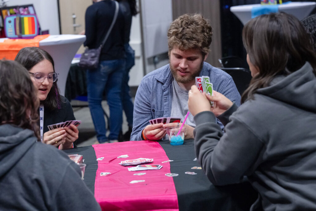 A group of people play a card game at a table.