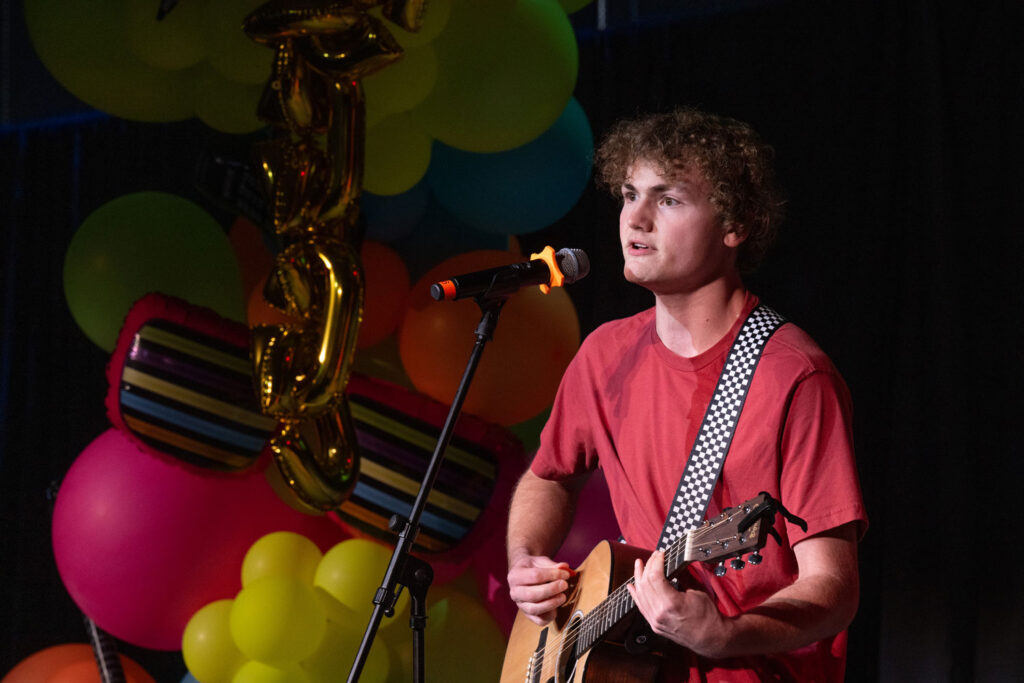 A person singing and playing the guitar.
