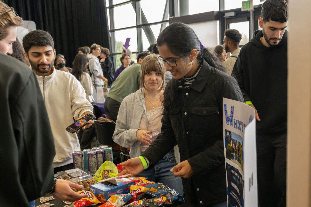 People around a table at a club fair event.