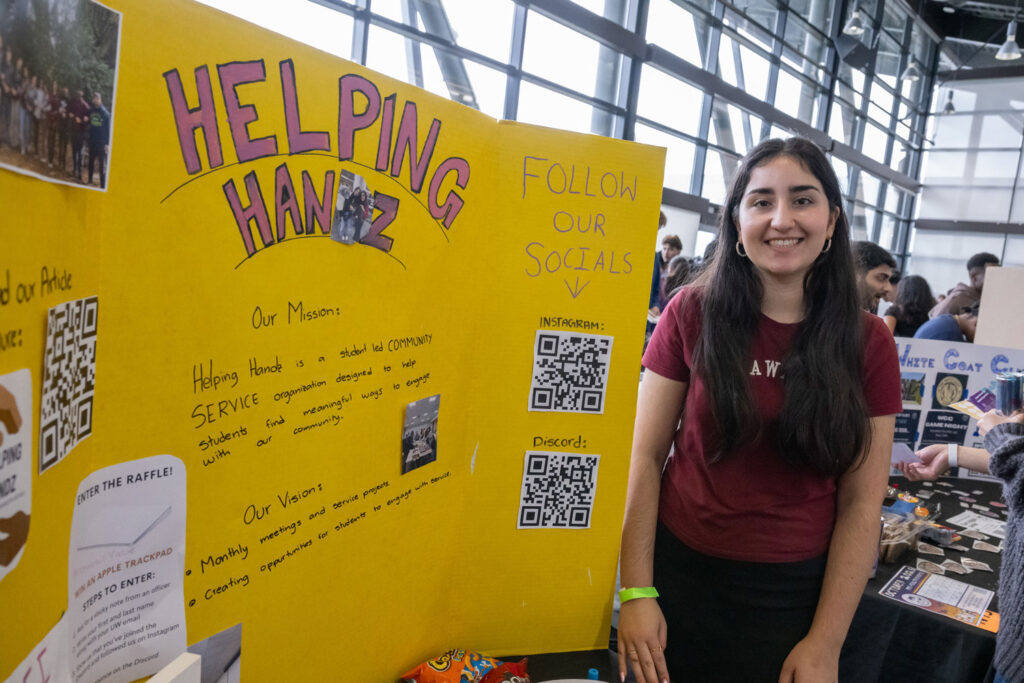 A person next to a poster that reads "Helping Handz."