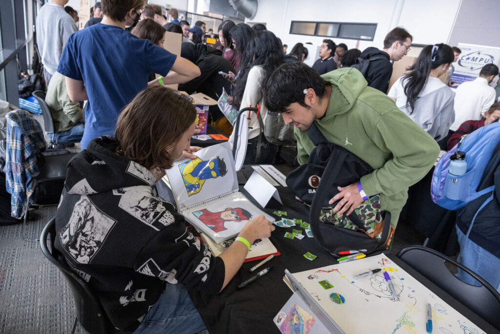People at a club fair looking at art.