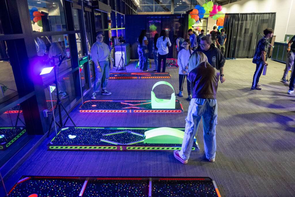 People playing glow-in-the-dark mini gulf.