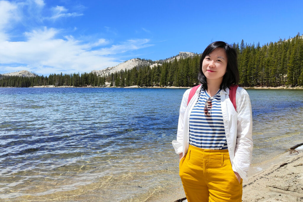 A person with a body of water and a mountain behind them.